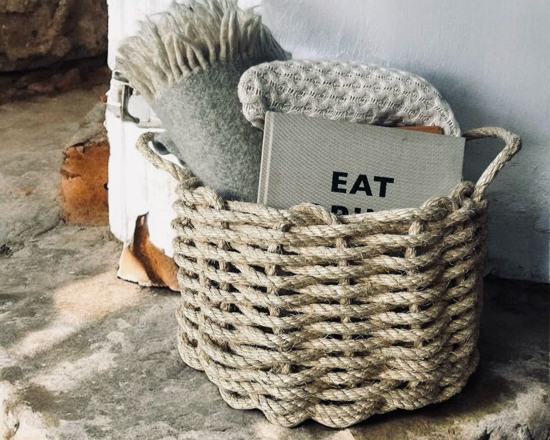 Handmade rope basket styled with books and blankets in a calm Cornish coastal interior